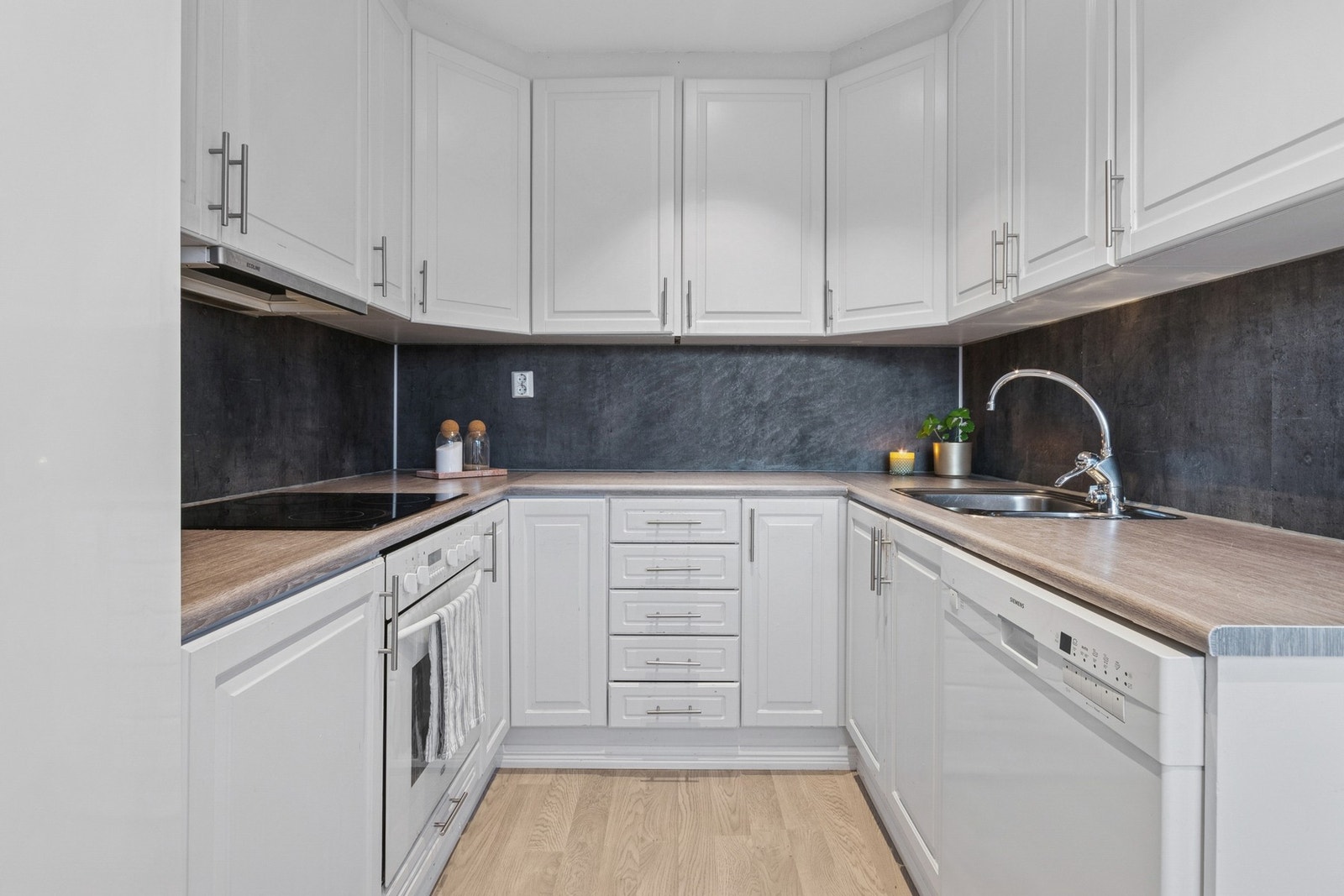 Kjøkkenet har innredning med profilerte fronter og kitchenboard på vegg over benkeplaten. Galleribilde