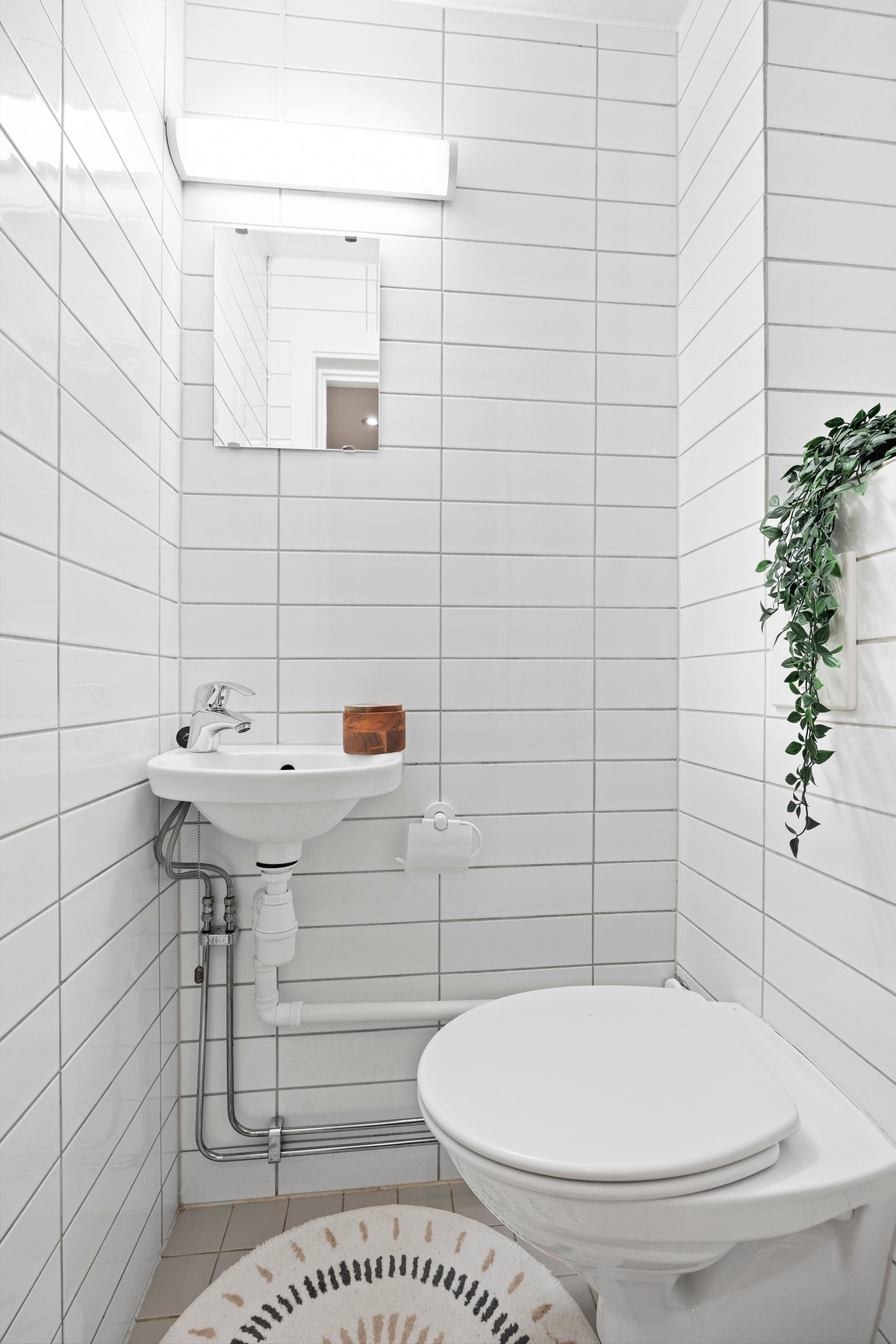 Flislagt toalettrom med vegghengt wc og servant. Galleribilde