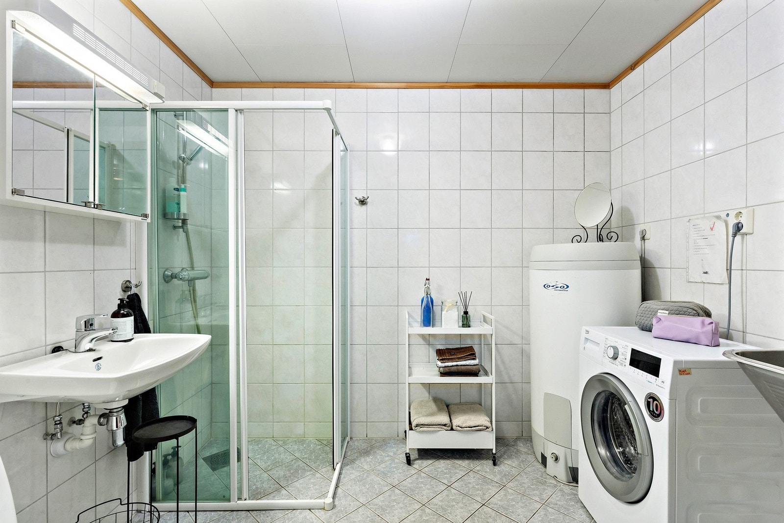 Stort og flislagt baderom utstyrt med gulvvarme og opplegg for for vaskemaskin. Galleribilde