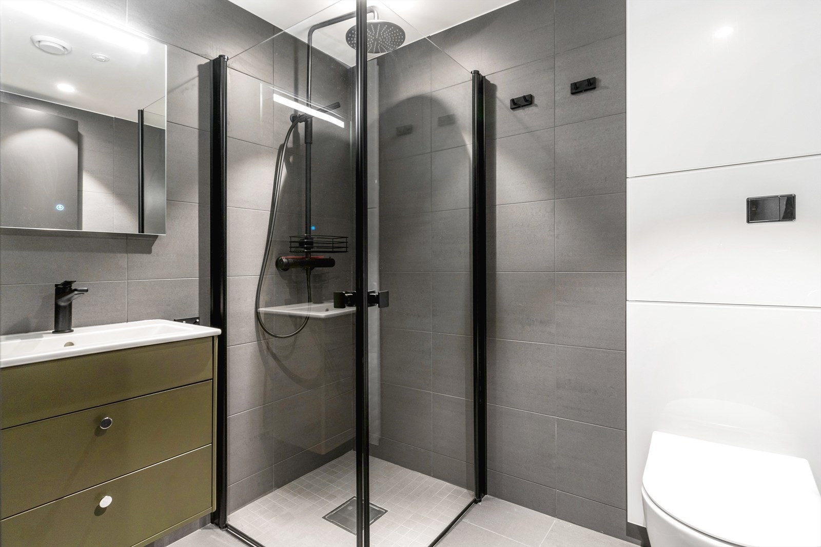 Leiligheten har to pene flislagte baderom. Det ene baderommet har adkomst fra entré/gang. Innredningen består av vegghengt toalett, dusjhjørne med regnfallsdusj og innfellbare glassdører, servant med underskuffer, og speil med integrerte LED-lys Galleribilde