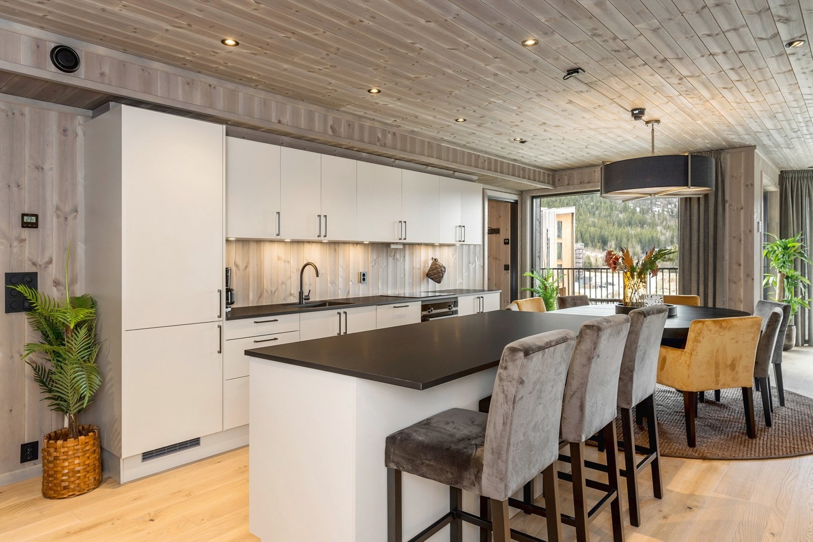 Kjøkkenet har en moderne og pen innredning bestående av hvite glatte fronter i både over- og underskap, belysning under overskap, laminat benkeplate med oppvaskkum, og en stor kjøkkenøy med sitteplasser Galleribilde