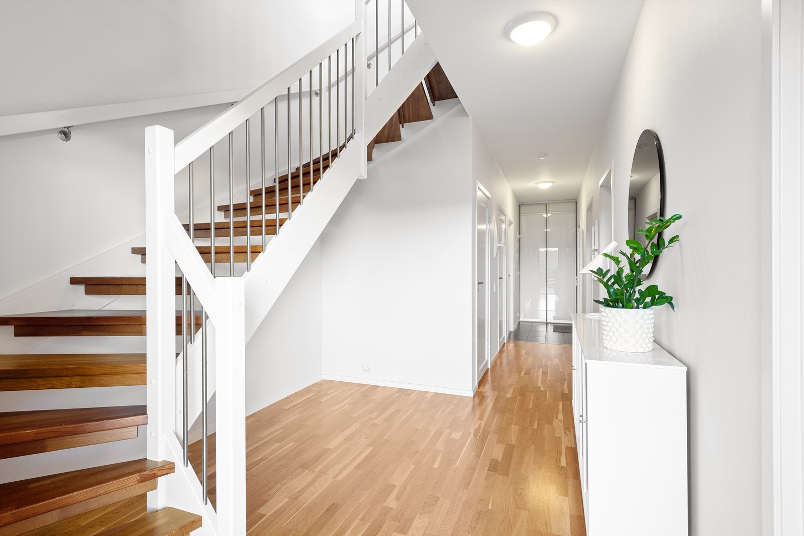 I boligens 1.etg er det entrè/hall med skyvedørsgarderobe, innredet bod i tilknytning til inngangsparti og en sone under trappen med mulighet for kontorplass eller lesekrok. Her har man også utgang til boligens markterrasse. Galleribilde