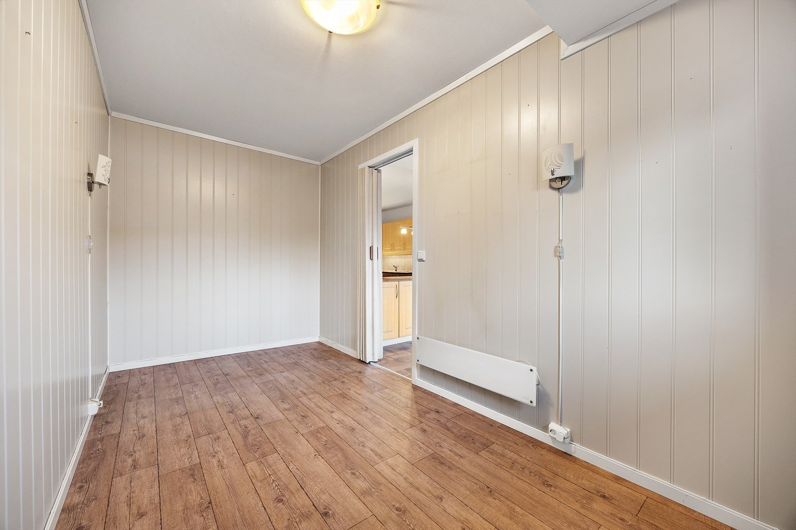 Rommet har panel på veggene og laminat på gulvet. Galleribilde