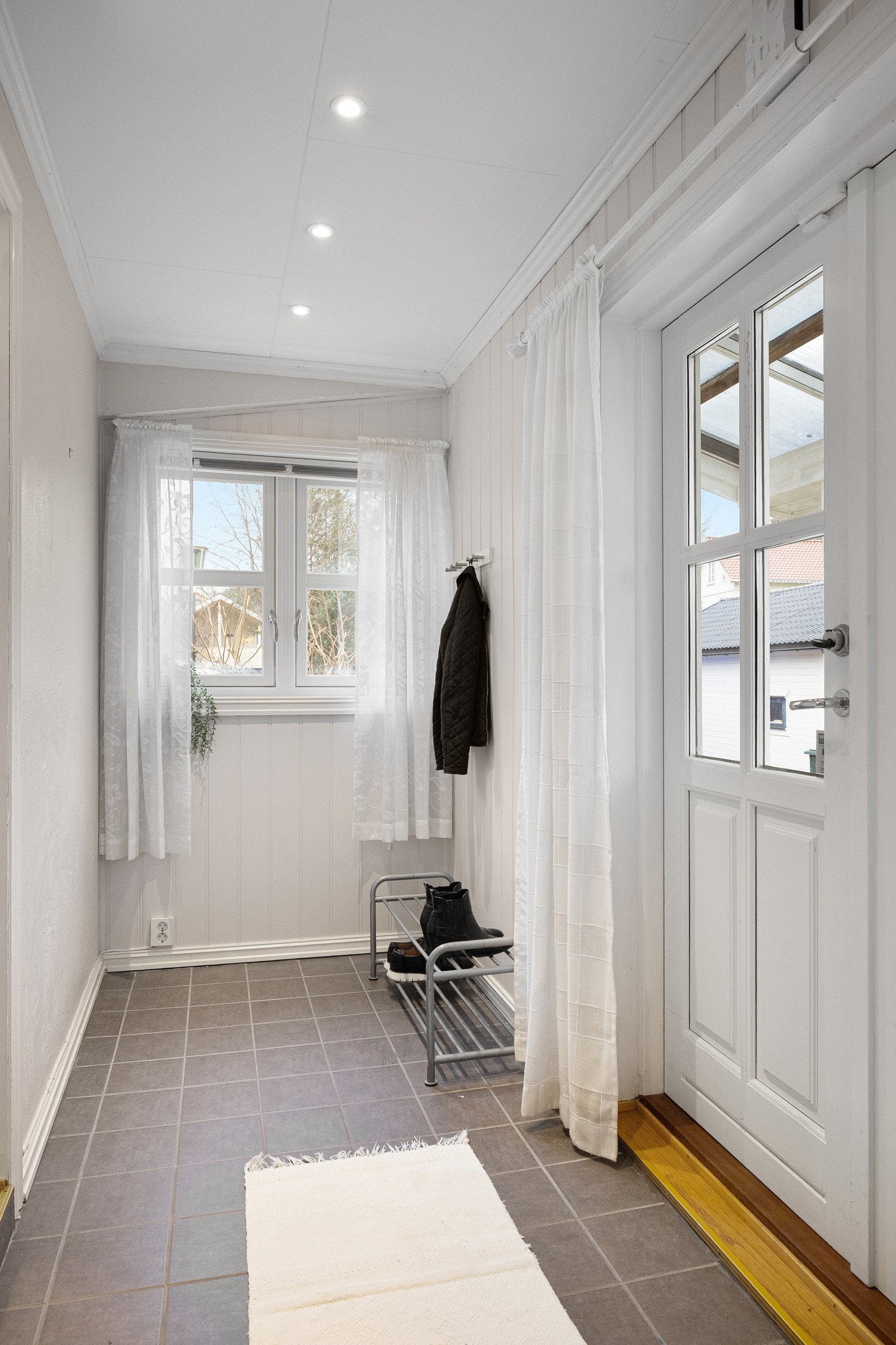 Inngangspartiet leder inn til en romslig entré med flislagt gulv, god plass til oppbevaring og naturlig lysinnslipp fra vinduer og doble ytterdører. Galleribilde