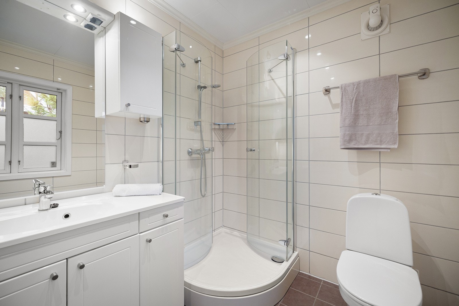 Badet fra 2011 fremstår med et lyst og tidløst uttrykk, innredet med dusjkabinett, gulvmontert toalett samt baderomsinnredning med nedsenket servant og speil. Galleribilde