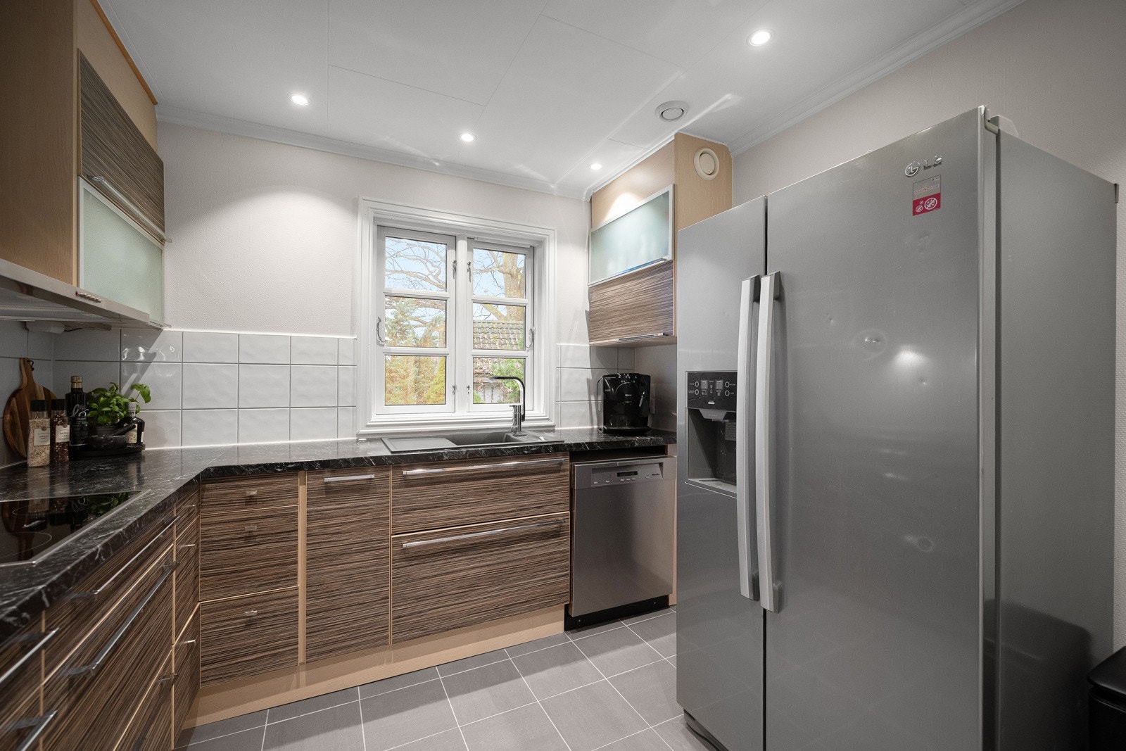 Kjøkkenet har en moderne innredning med glatte og delvis glassede fronter, kombinert med laminat benkeplate. Galleribilde