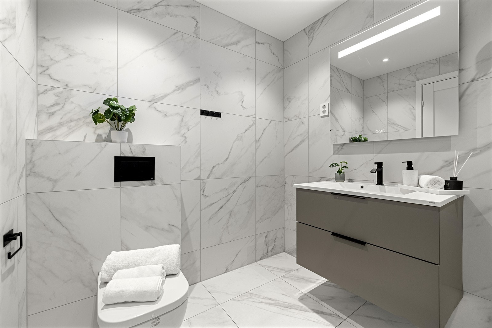 Badet er utstyrt med vegghengt toalett, servant med skuffer og dusjnisje med innfellbare glassvegger. Galleribilde