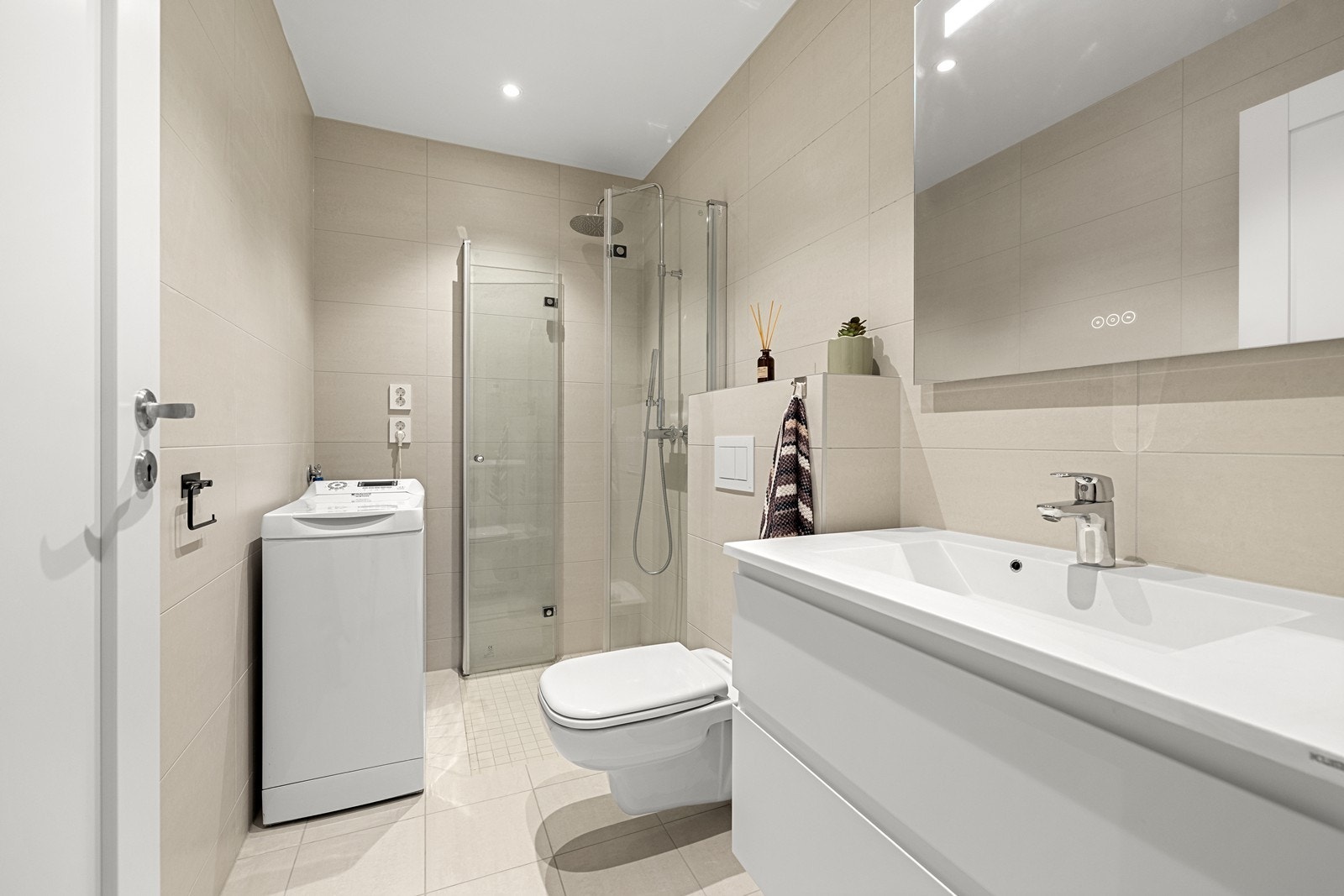 Badet er helfliset med vannbåren gulvvarme, veggmontert toalett, dusjhjørne og opplegg for vaskemaskin. Galleribilde