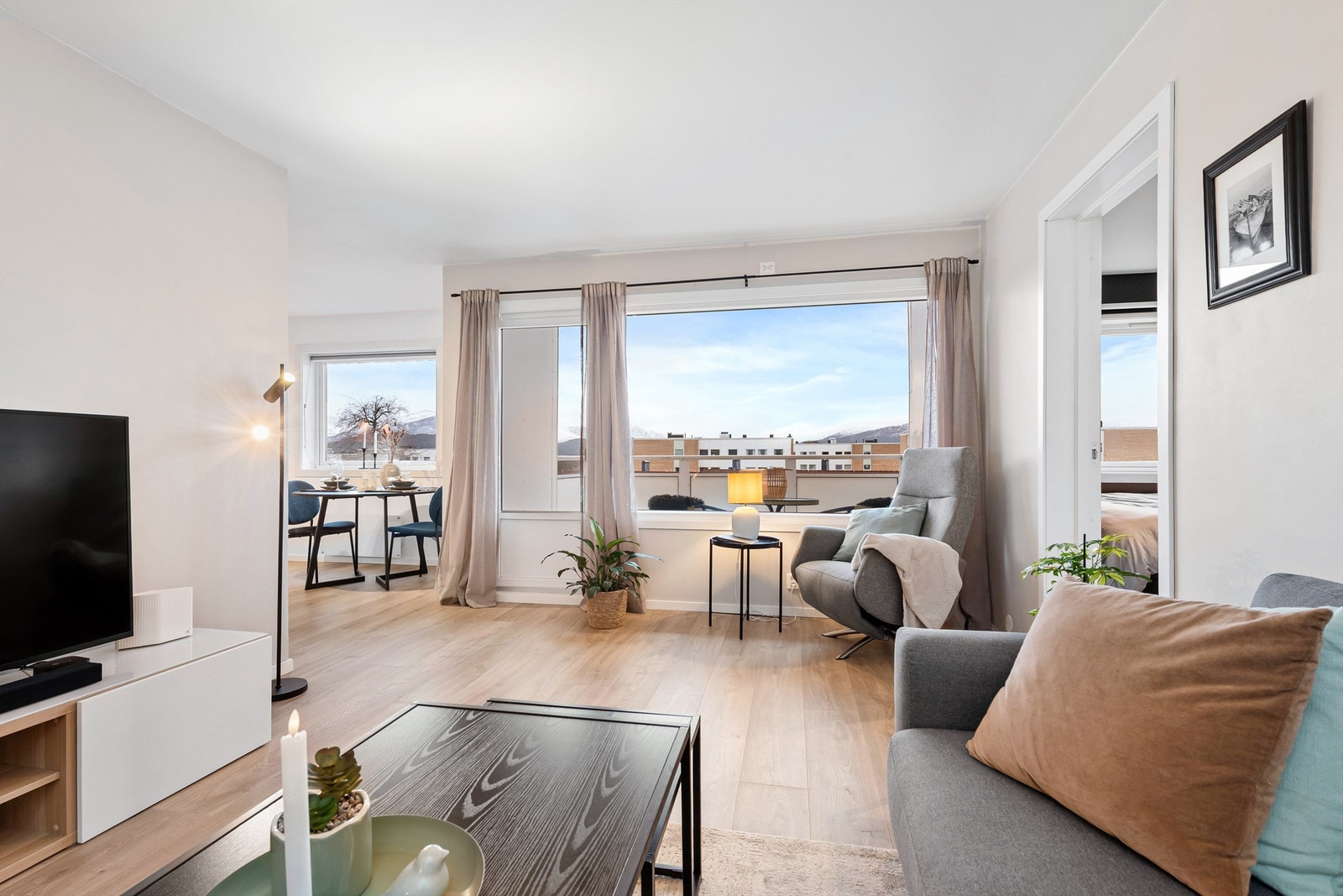 Stue og kjøkken i dels åpen løsning med lyse overflater og godt med naturlig lysinnslipp fra vinduer Galleribilde