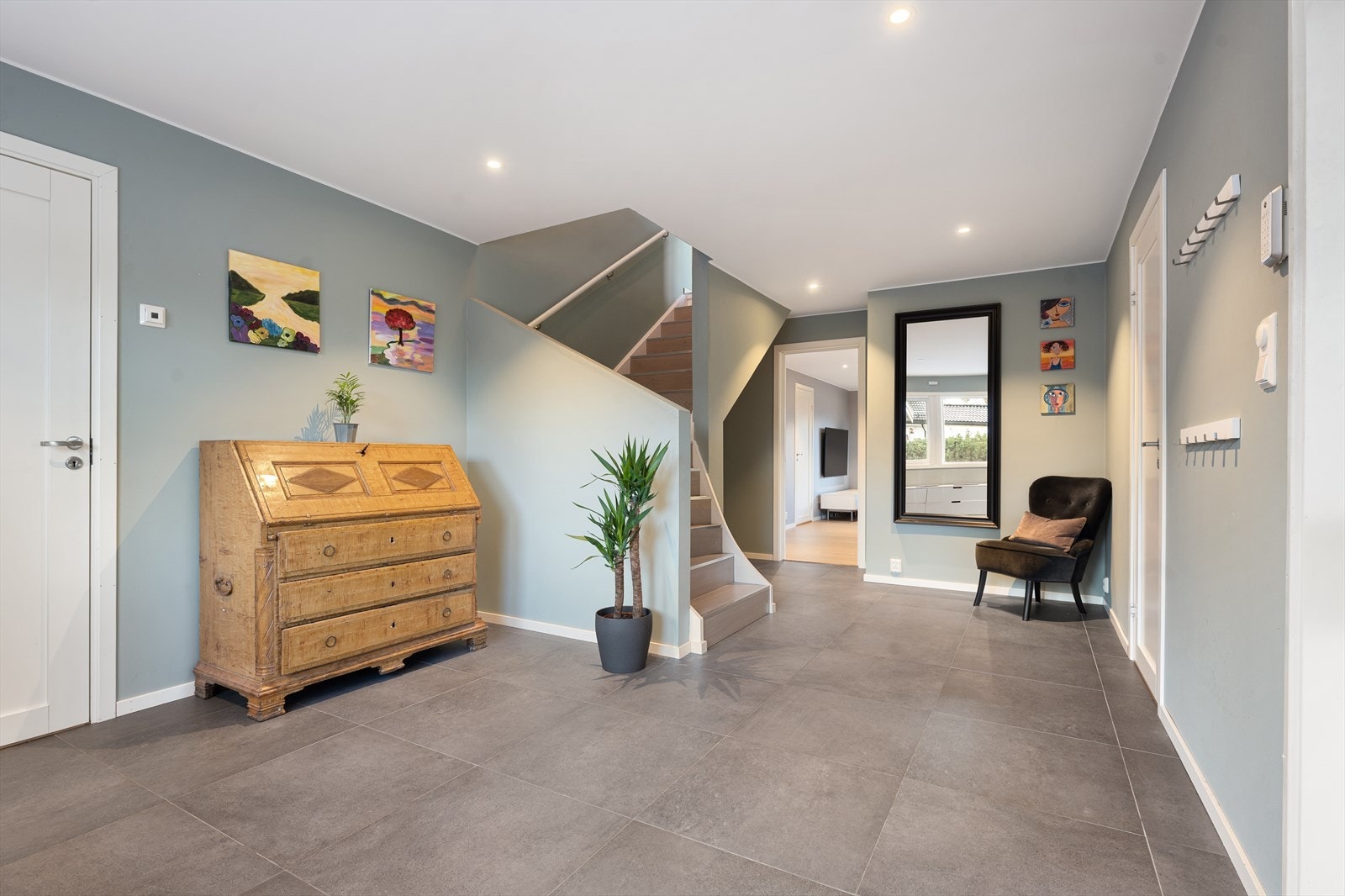 Hallen fungerer som et knutepunkt i etasjen og leder videre til de øvrige rommene via en vinkeltrapp i tre. Galleribilde