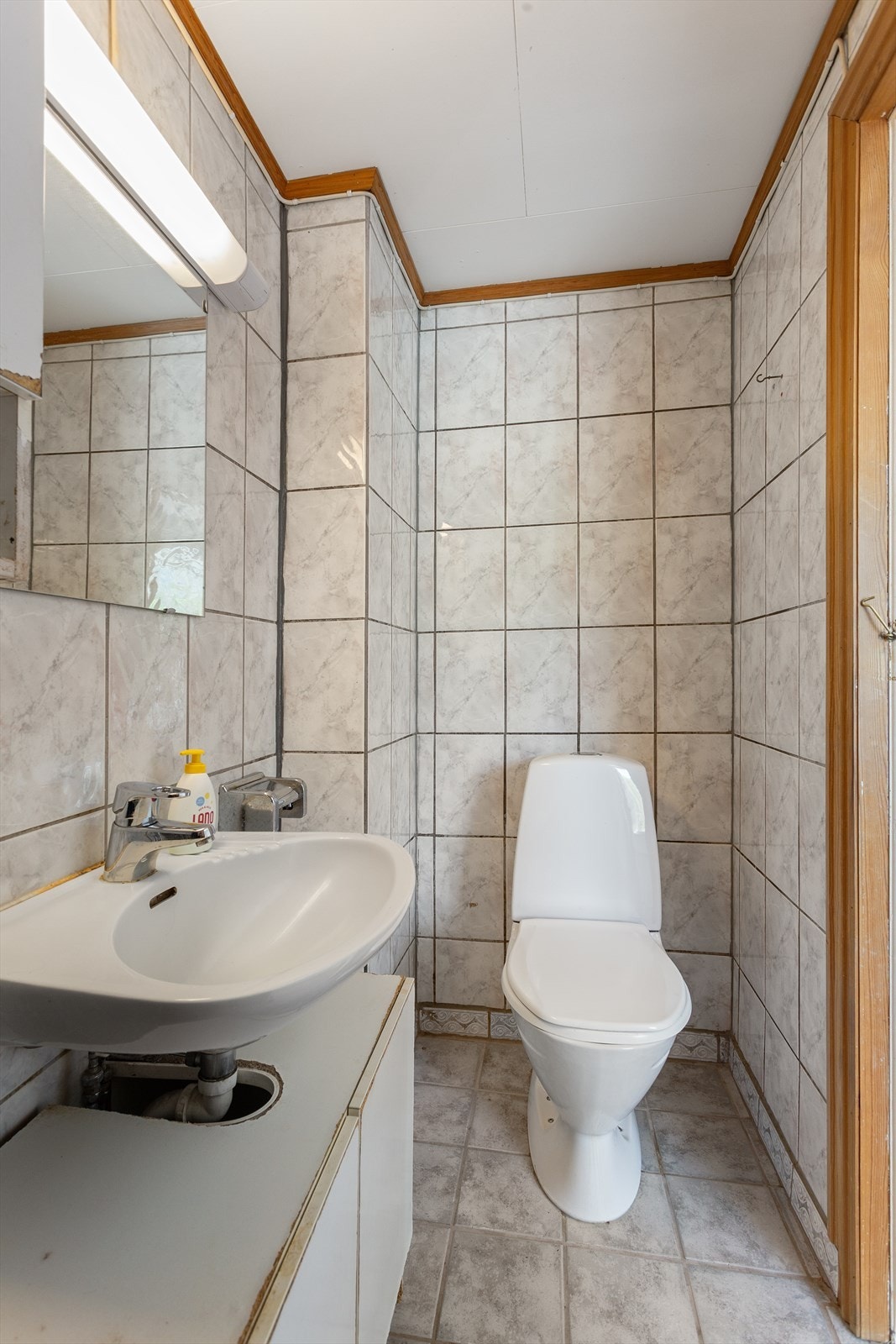 Flislagt bad med vegghengt servant og gulvstående toalett Galleribilde