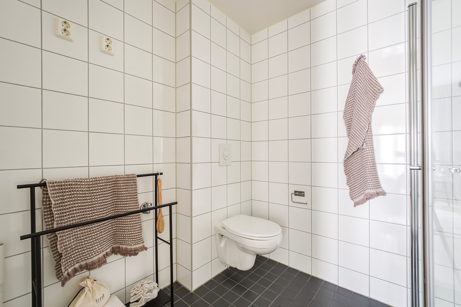 Videre er badet innredet med nedfelt servant med underskap, speil, vegghengt toalett og dusjhjørne. Galleribilde