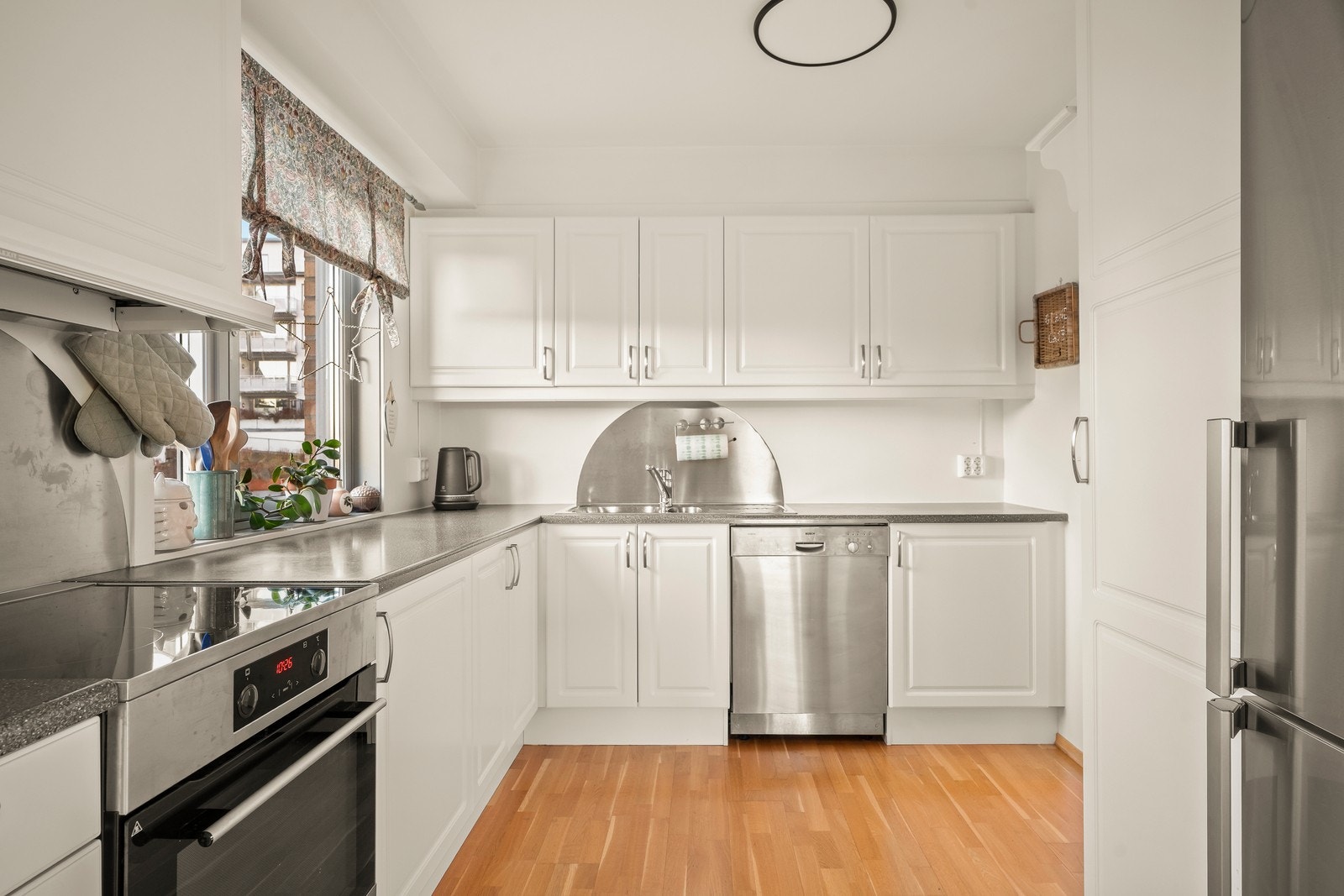 Kjøkkenet er utstyrt med frittstående hvitevarer som komfyr, oppvaskmaskin samt kjøl/fryseskap. Det er montert beskyttelsesplate på vegg over benkeplaten ved både vask og komfyr. Ventilator plassert over komfyr med avtrekk ut. Galleribilde