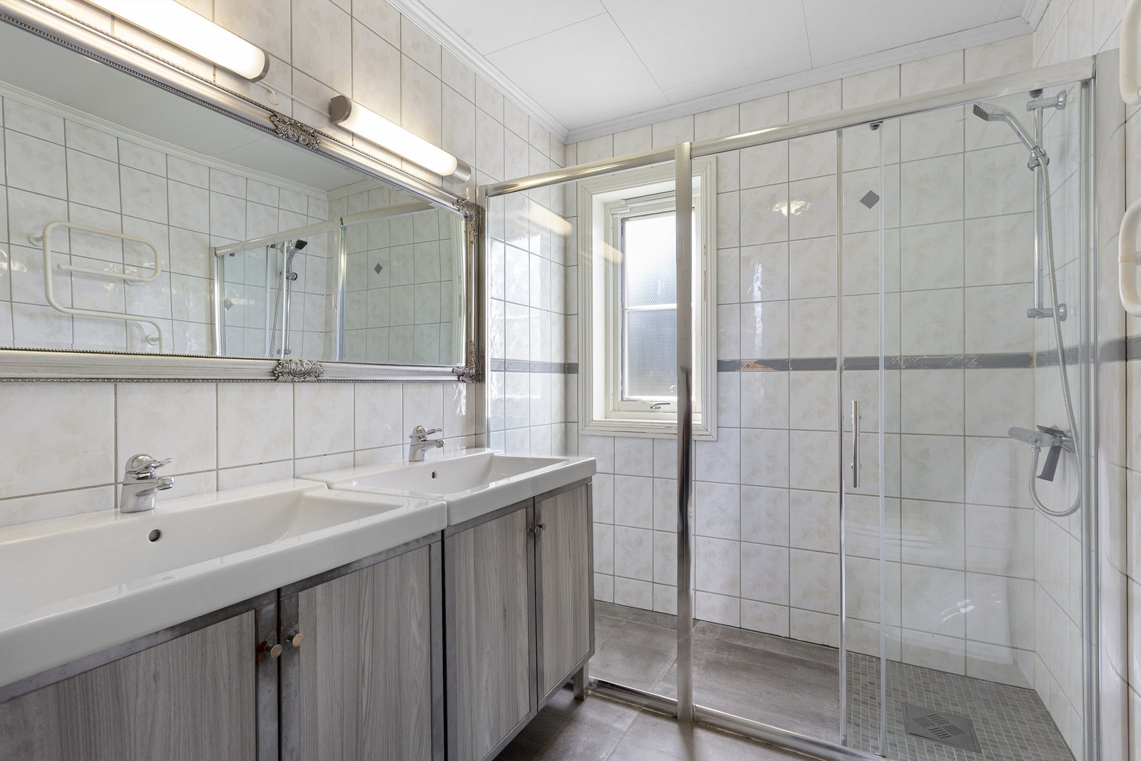 Bad med romslig dusjnisje som har skyvedørsramme av glass samt veggmontert dusjarmatur Galleribilde