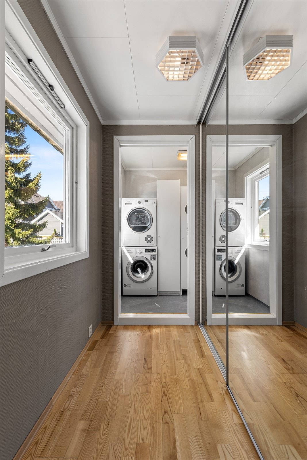 Mellomgang med skyvedørsgarderobe som har speilfronter Galleribilde