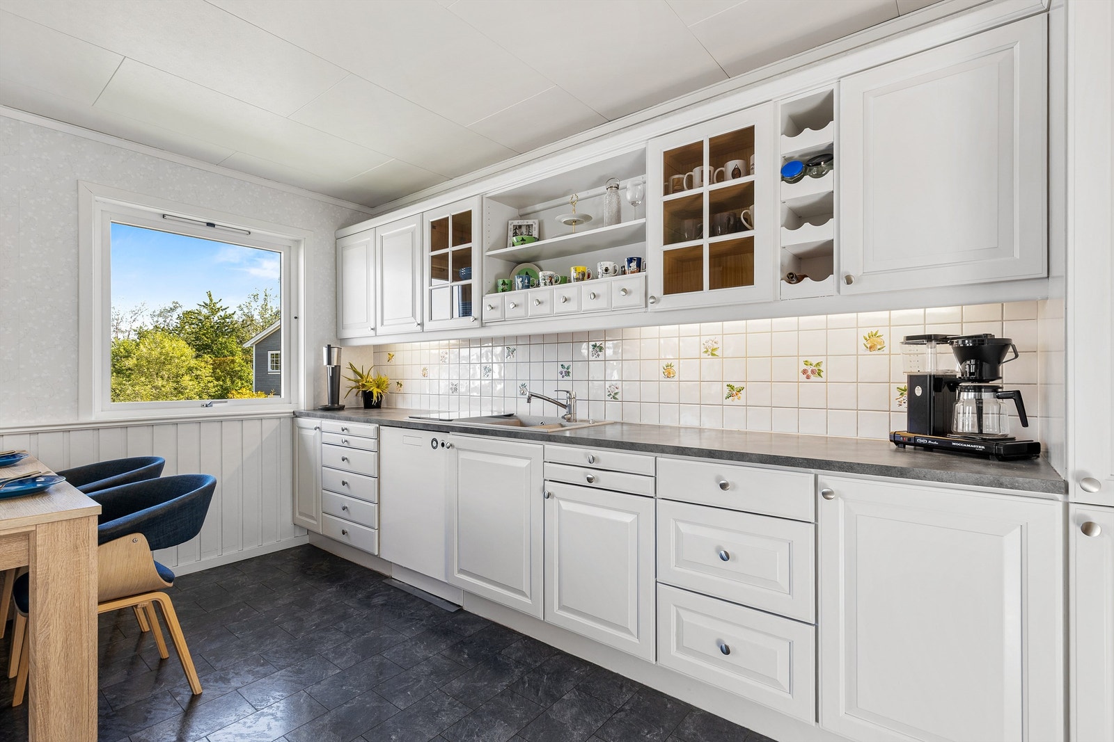 Flislagte felt på vegg over laminerte benkeplater og lysarmaturer under overskap Galleribilde