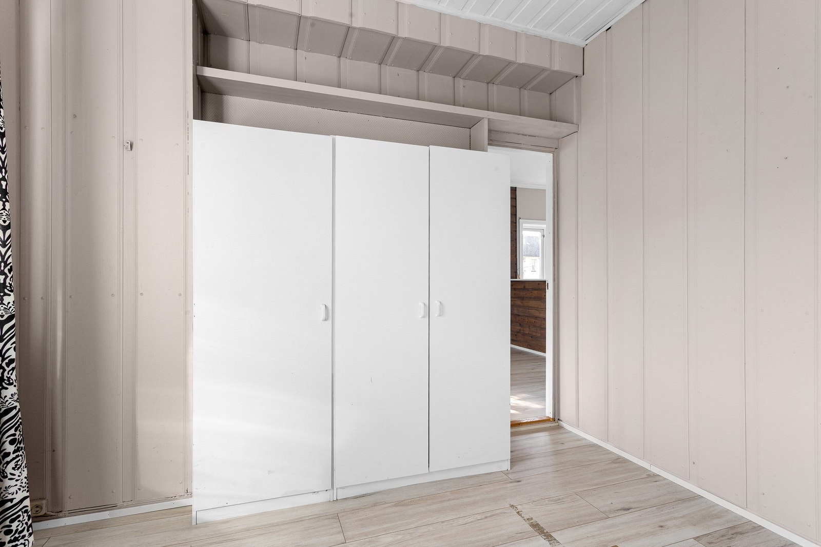 Laminat på gulv, malt panel på vegger og malt panel med synlige takbjelker i himling Galleribilde