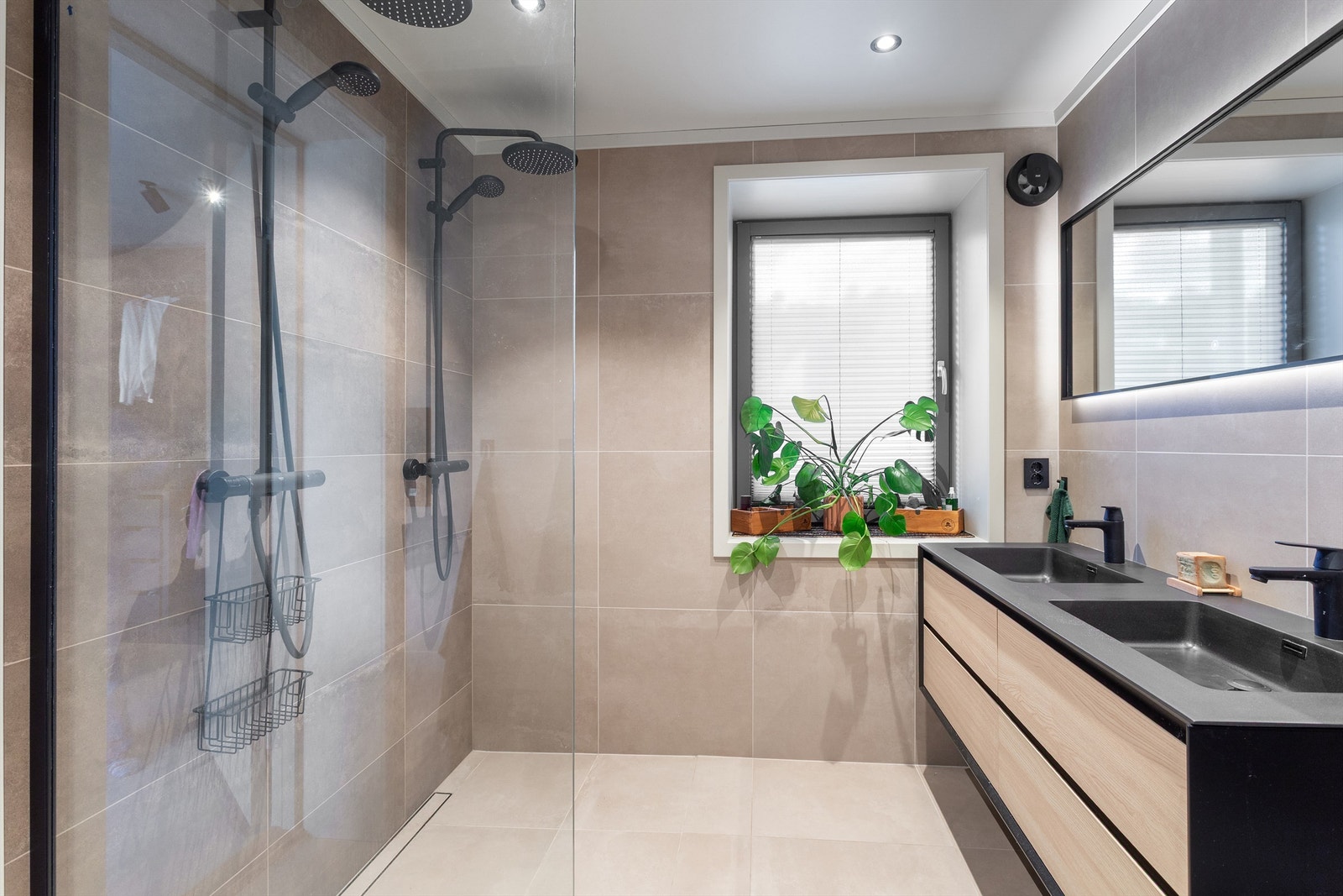 Badet har heldekkende dobbelservant og to veggmonterte regnfallsdusjer Galleribilde