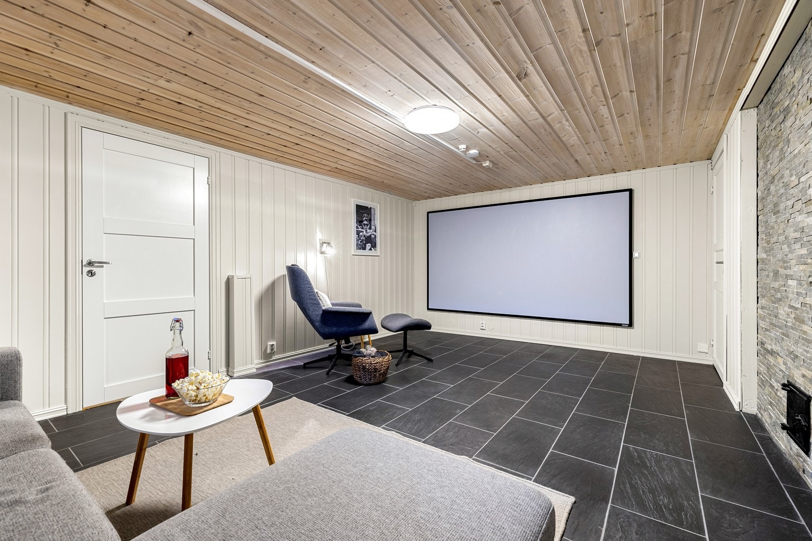 Stuen er møblert som TV-stue med flislagt gulv og panelte overflater. Galleribilde