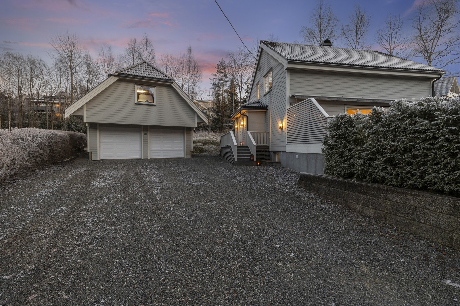 Dobbelgarasje fra 2004 med elektriske portåpnere og gruset gårdsplass. Galleribilde