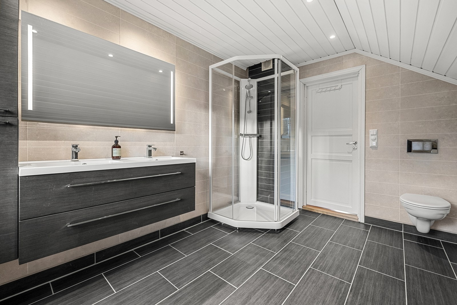 Badet har flislagt gulv med varmekabler og våtromsplater med flismotiv på veggene. Galleribilde