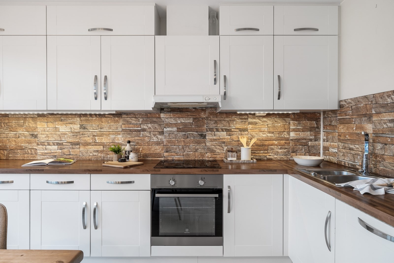 Kjøkkenet er praktisk plassert i en vinkelform og har en lys og klassisk innredning i malt utførelse. Galleribilde