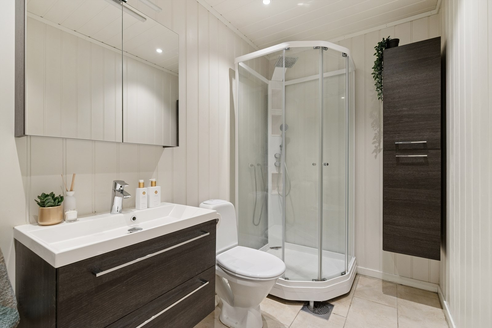 Flislagt gulv med varmekabler - badet er utstyrt med dusjkabinett, servant med underskap og speilskap, samt vegghengt oppbevaringsskap. Galleribilde