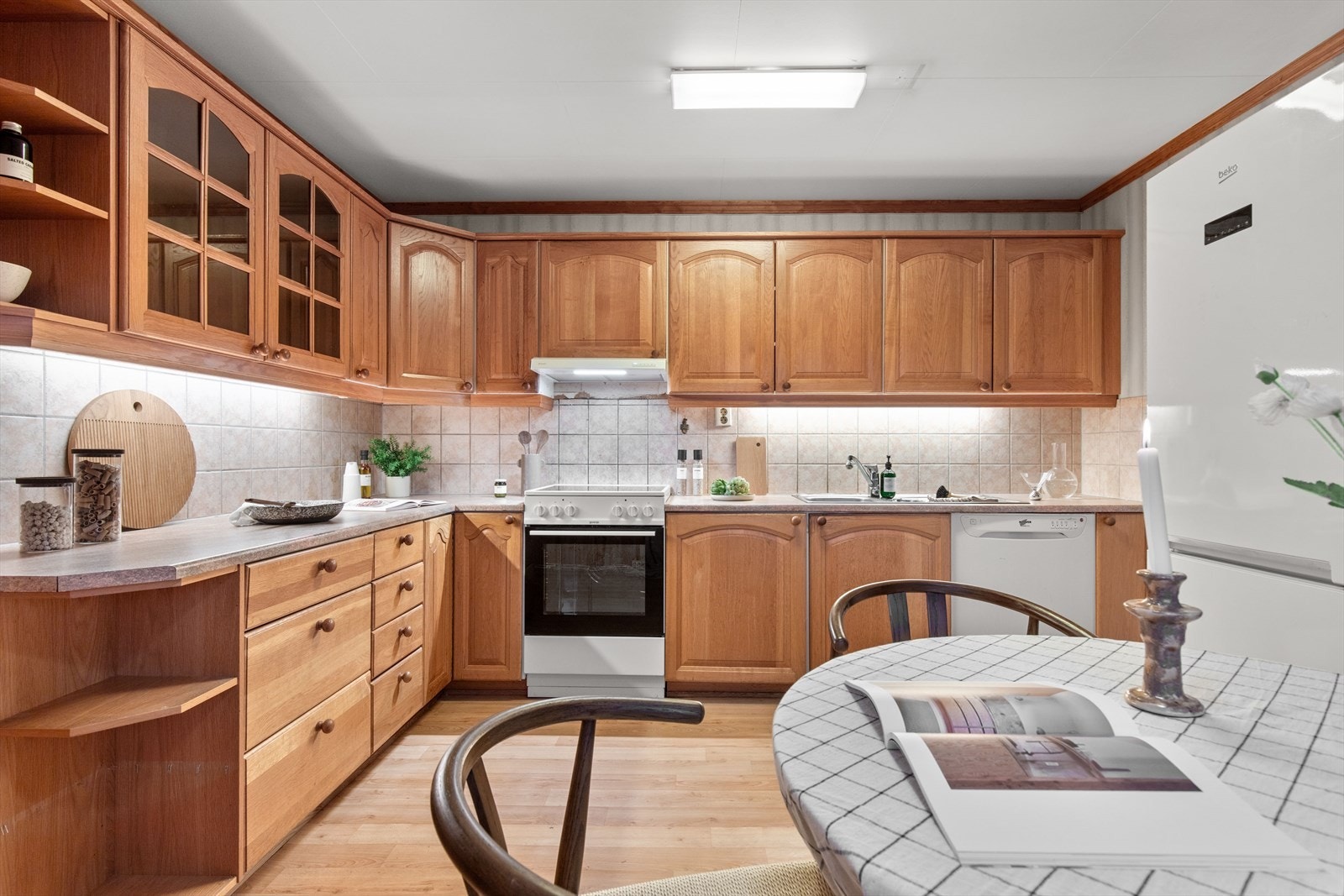 Separat kjøkken med profilerte fronter og vitrineskap, benkeplate i laminat og frisstående hvitevarer. Galleribilde