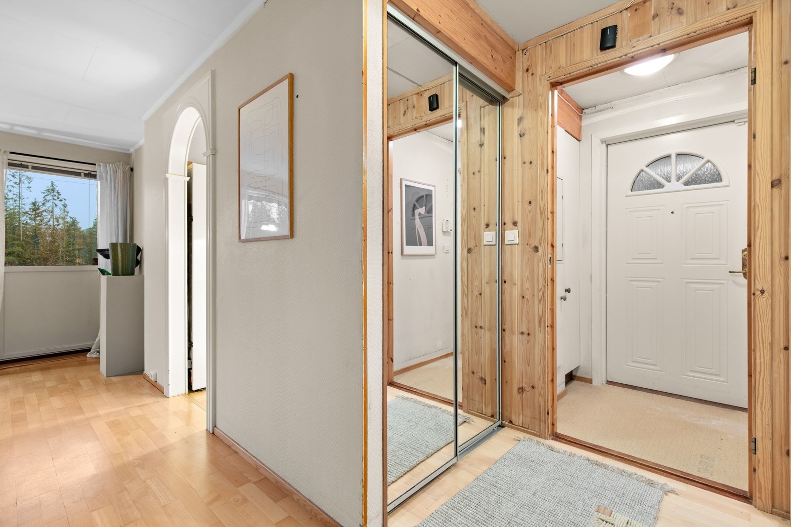 Skyvedørsgarderobe gir effektiv oppbevaring i entréen, som har parkettgulv og panelte vegger. Galleribilde