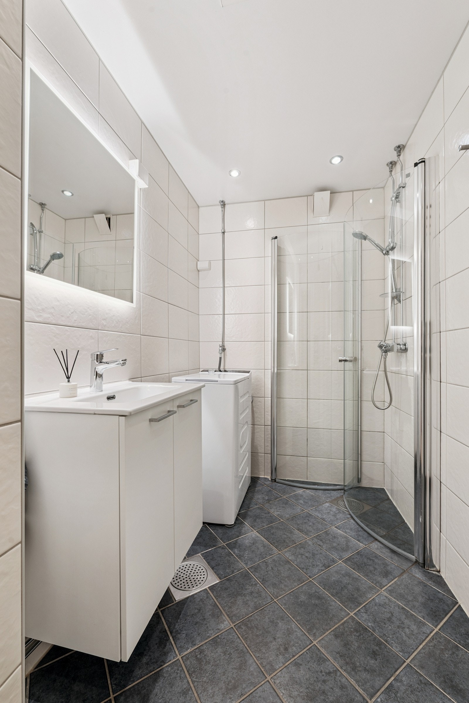 Flislagt pent baderom med gulvvarme. Praktisk innredet og med opplegg for vaskemaskin. Galleribilde