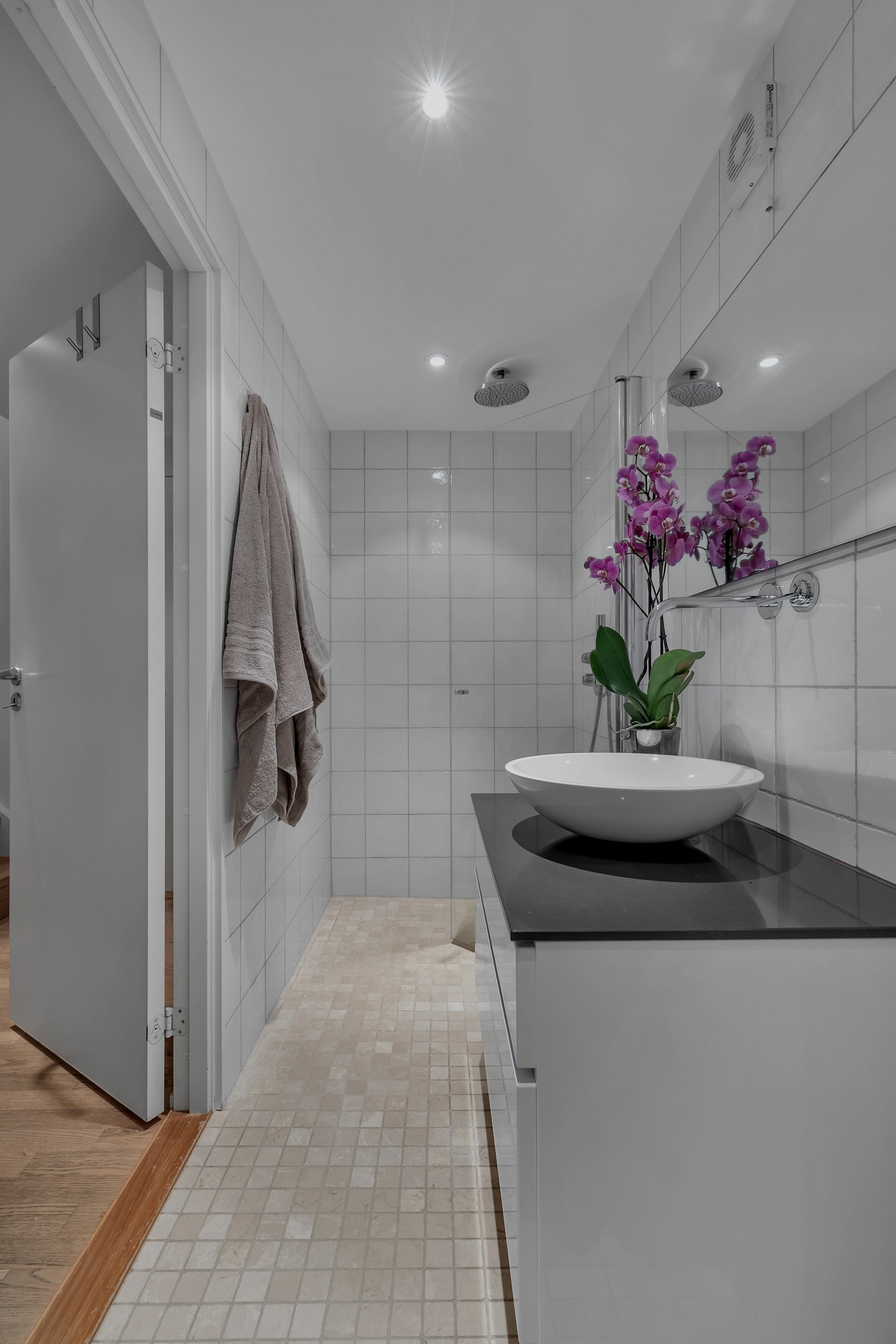 Badet er pent flislagt med mosaikkfliser på gulv, har en praktisk innredning med god laringsplass, innfelt belysning i tak m.m. Galleribilde