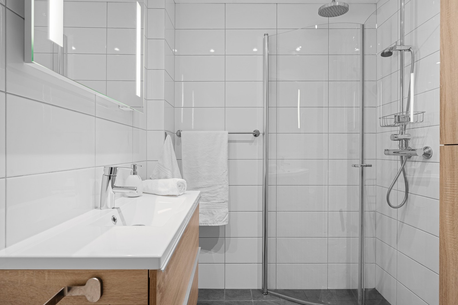 Fint fliselagt baderom med servantinnredning m/speil, dusjhjørne, vegghengt toalett og opplegg til vaskemaskin. Galleribilde