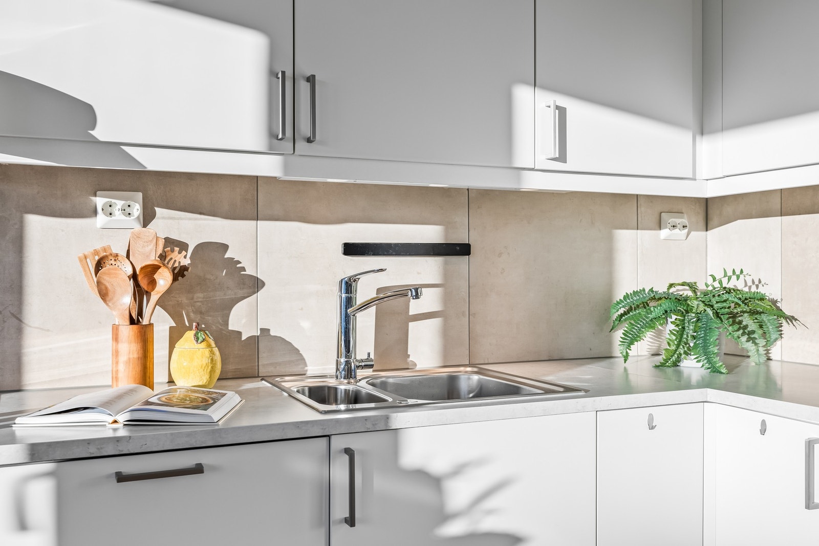 Flott kjøkken med takhøy innredning, downlights under overskapq og flisfelt på vegg Galleribilde