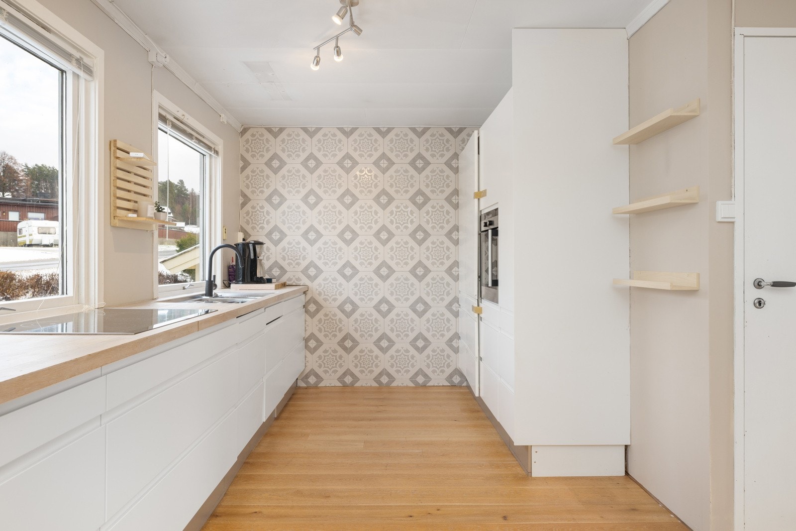 Lyst kjøkken med god skapplass, åpne hyller og hyggelig spiseplass ved vindu. Galleribilde