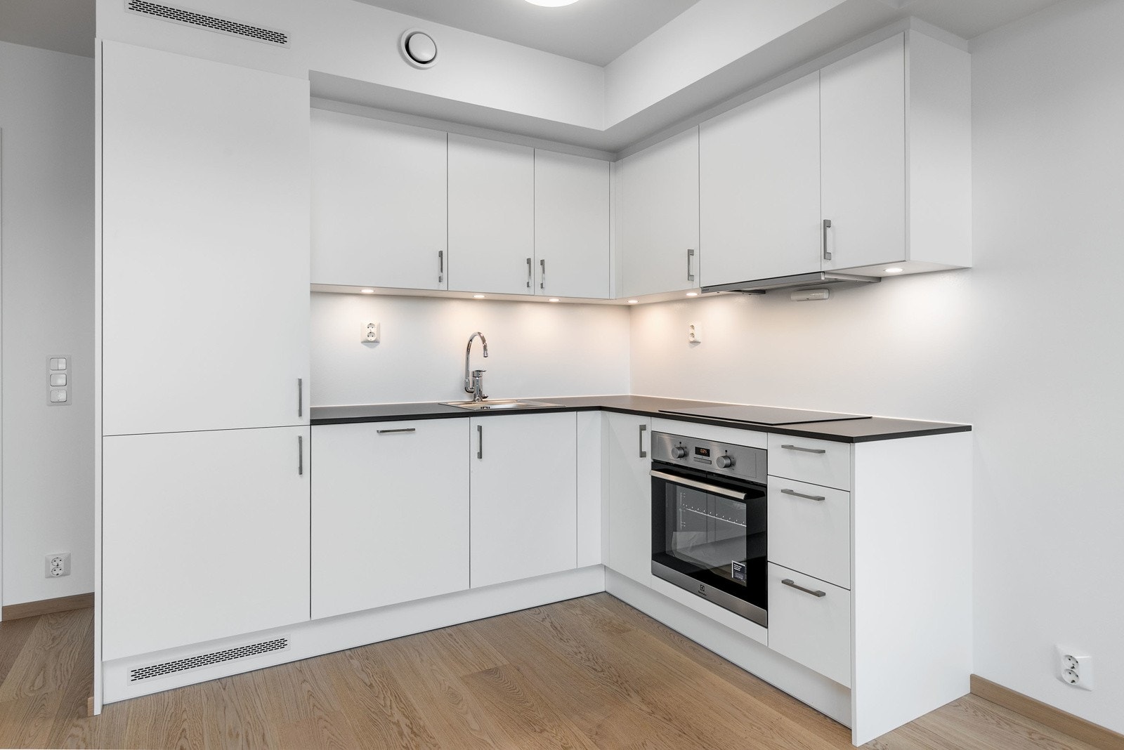 Lekkert kjøkken i åpen løsning mot stue, med integrerte hvitevarer Galleribilde