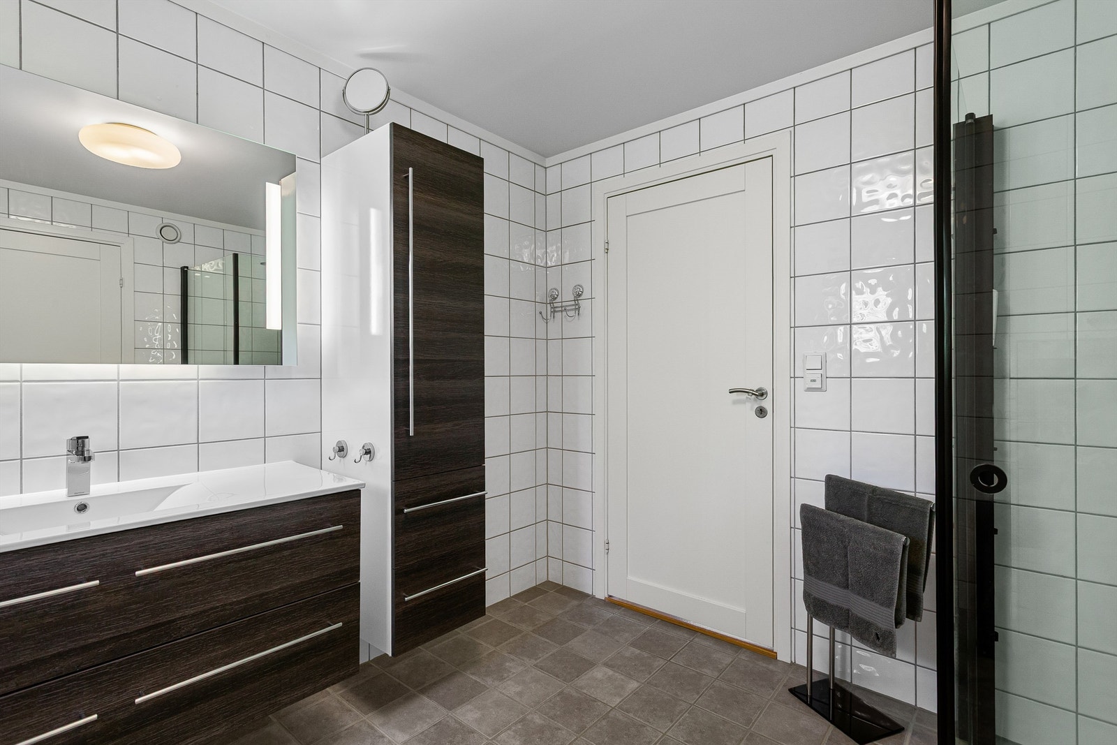 Badet har dusjhjørne med foldedører av glass og regnfallsdusj Galleribilde