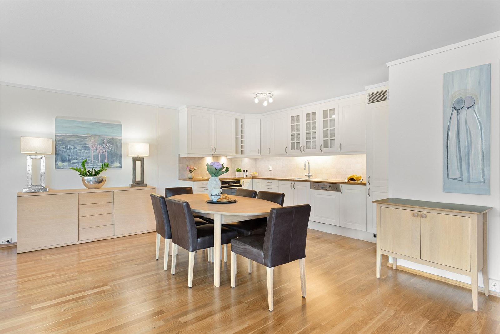 Flislagt felt på vegg over benkeplater av laminat og lysarmaturer under overskap Galleribilde