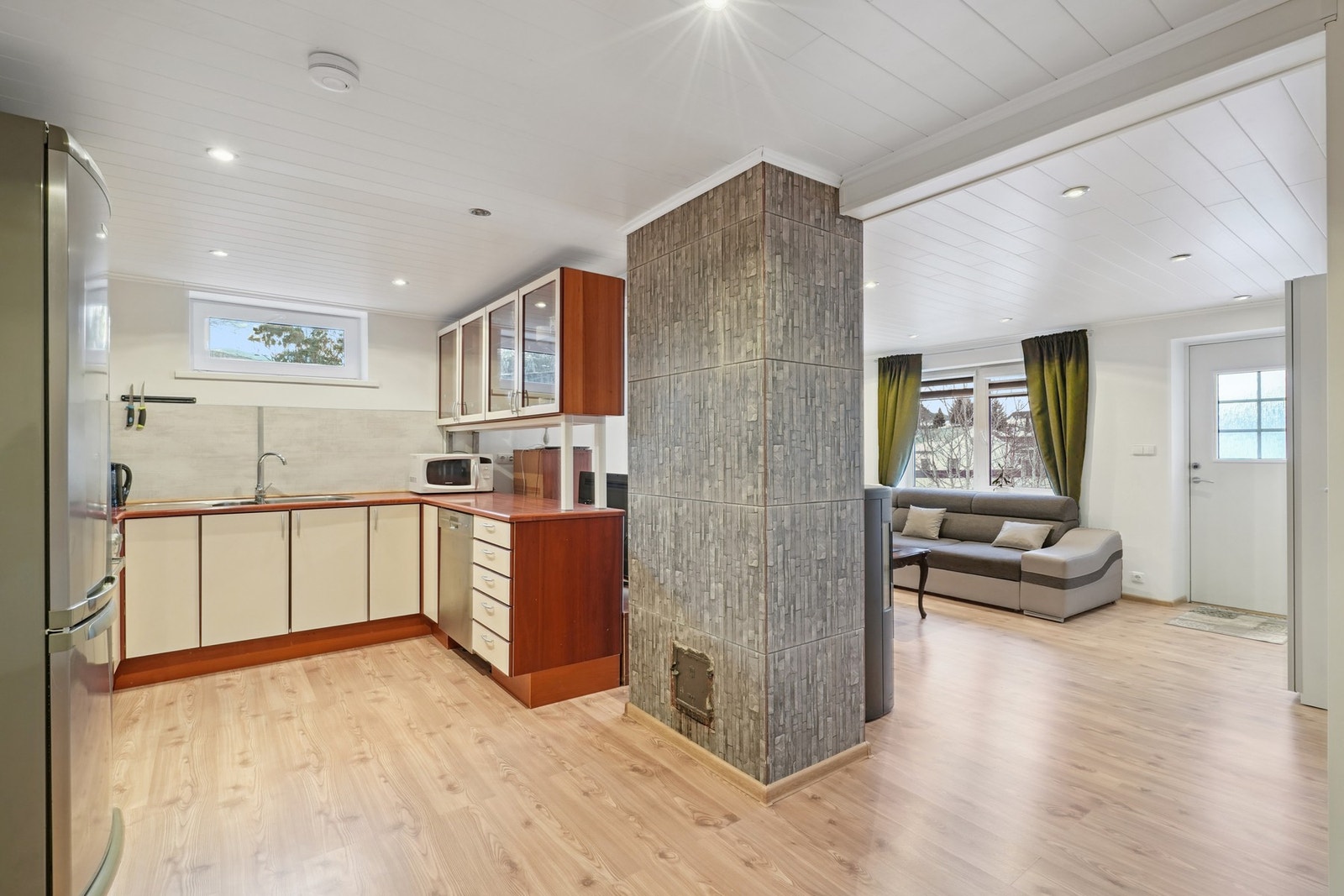 Kjøkkenet har en praktisk utforming med rikelig av skap- og skuffeplass. Kjøkkeninnredningen har hvite glatte fronter og en laminat benkeplate. Galleribilde