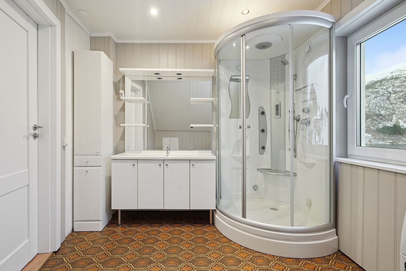 Badet har vinylbelegg på gulvet. Det er utstyrt med baderomsinnredning med skapfronter, dusjkabinett og toalett. Galleribilde