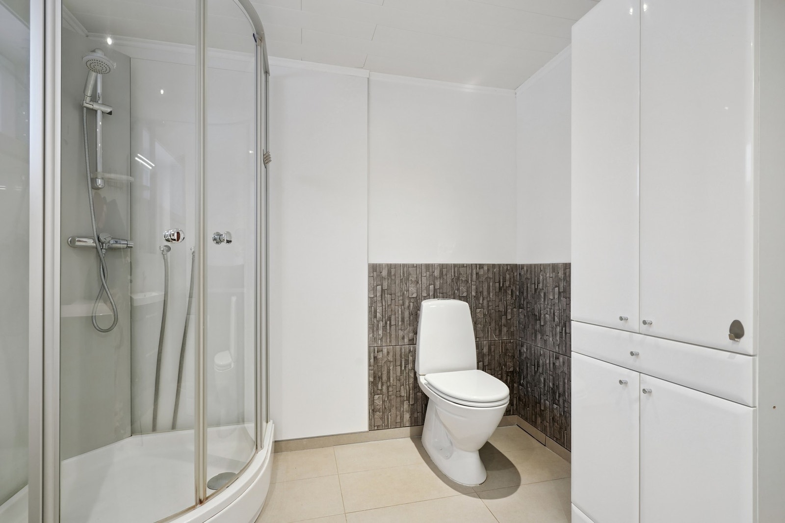 Det er utstyrt med dusjkabinett, baderomsmøbel og toalett. Rommet kombineres med vaskerom og har opplegg for vaskemaskin. Galleribilde