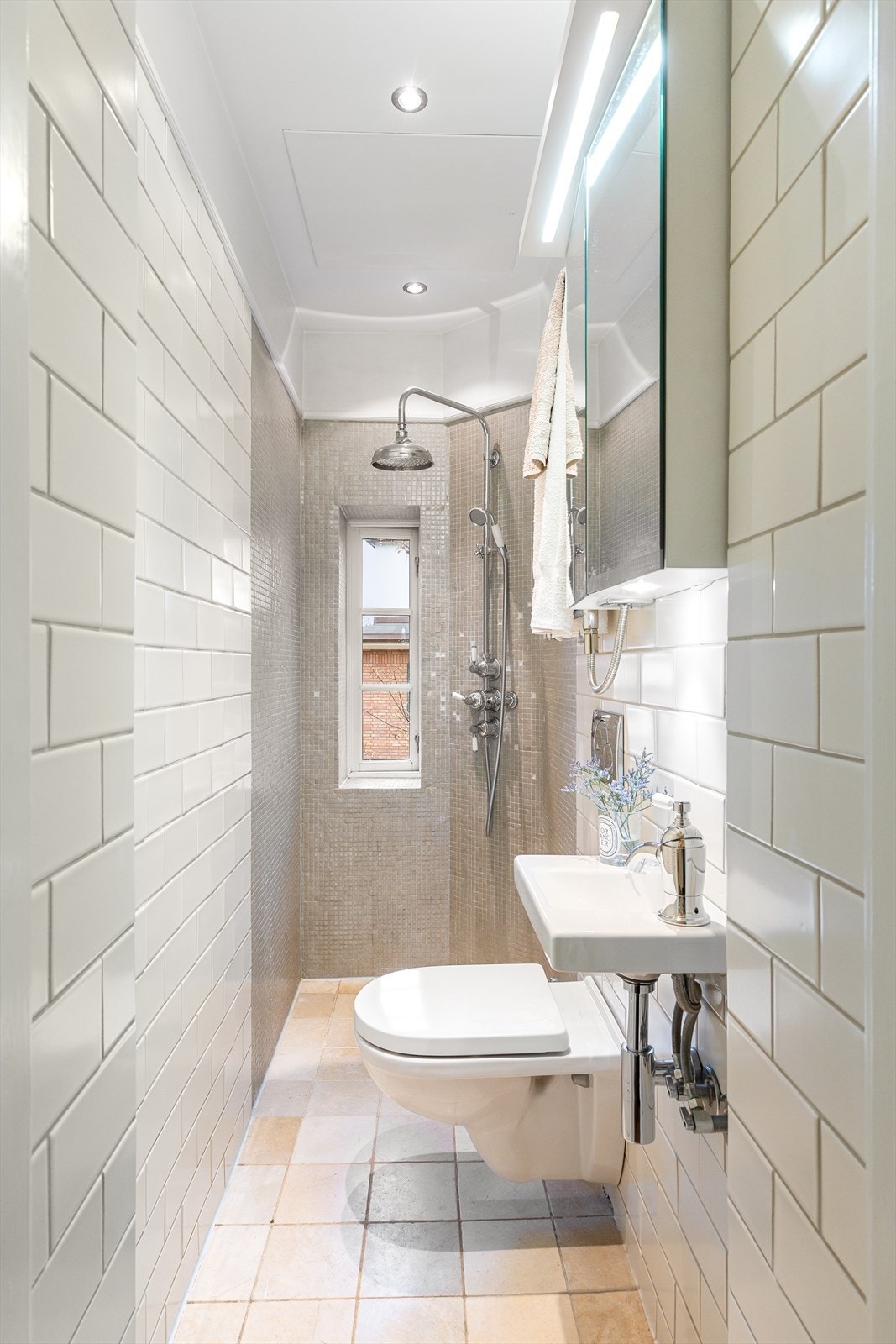 Praktisk bad med fliser på gulv og vegger, downlights og malt himling. Gulvvarme gir god komfort. Rommet har naturlig avtrekk, åpen dusj, veggmontert wc og servant med ettgreps blandebatteri. Galleribilde