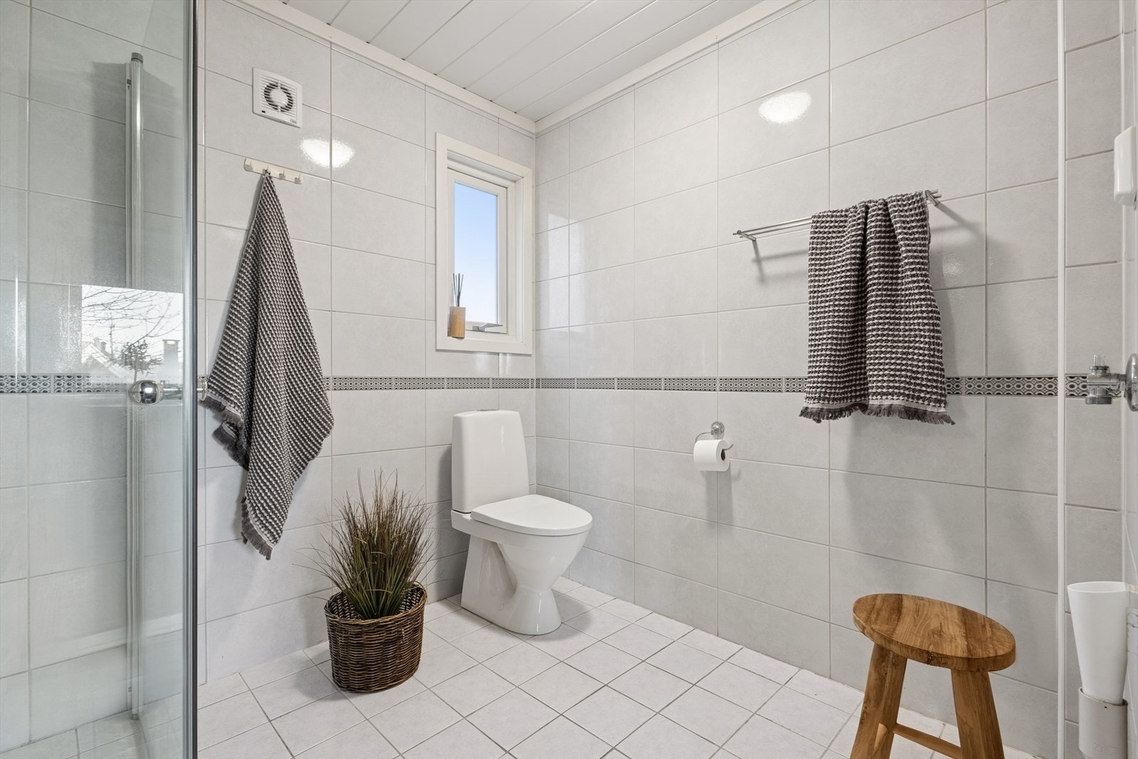 Gulvmontert WC og flislagte overflater gir praktisk brukervennlighet, med tilluft ved døren. Galleribilde