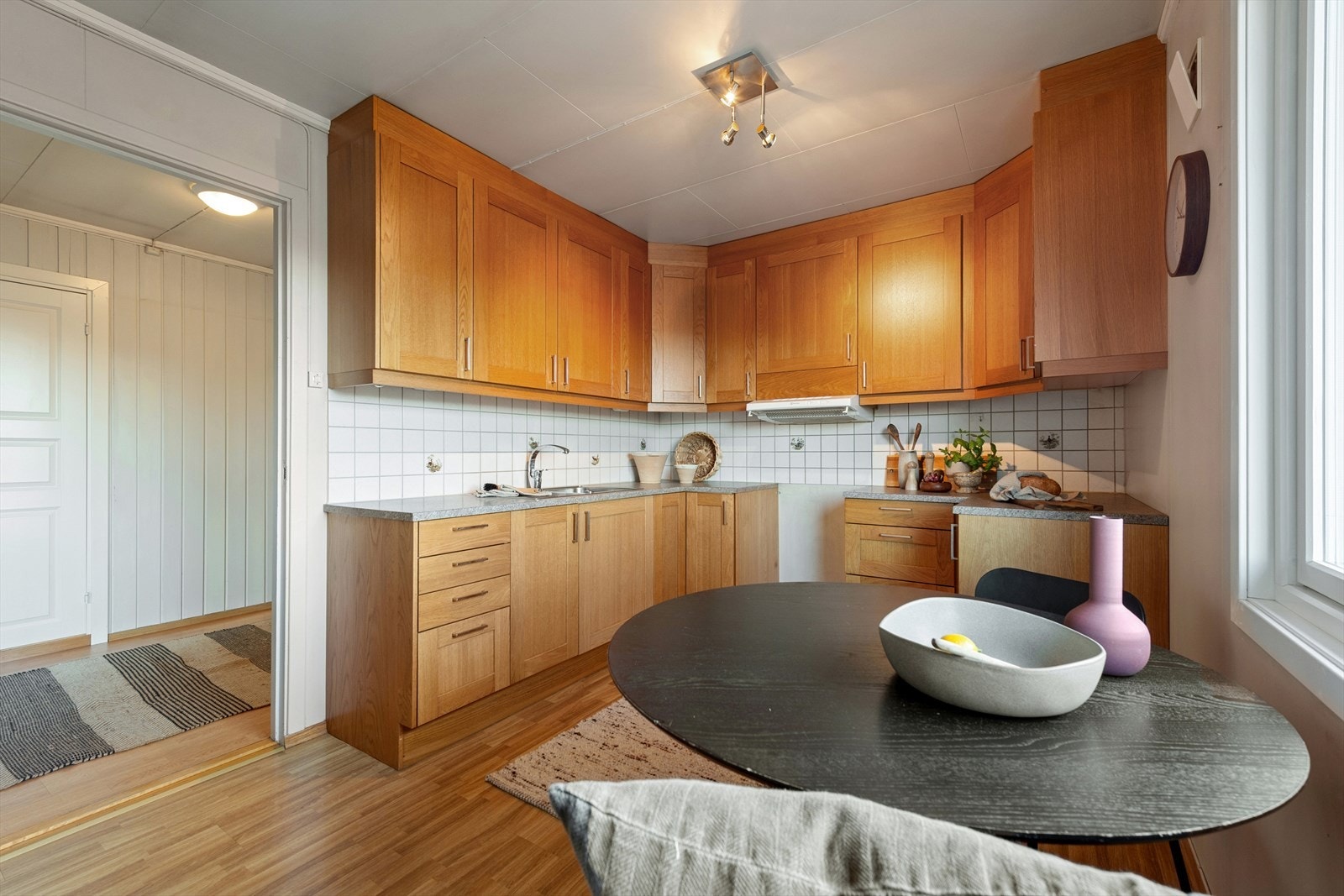 Kjøkkenet har profilerte fronter og laminert benkeplate med fliser over arbeidsområdet. Galleribilde