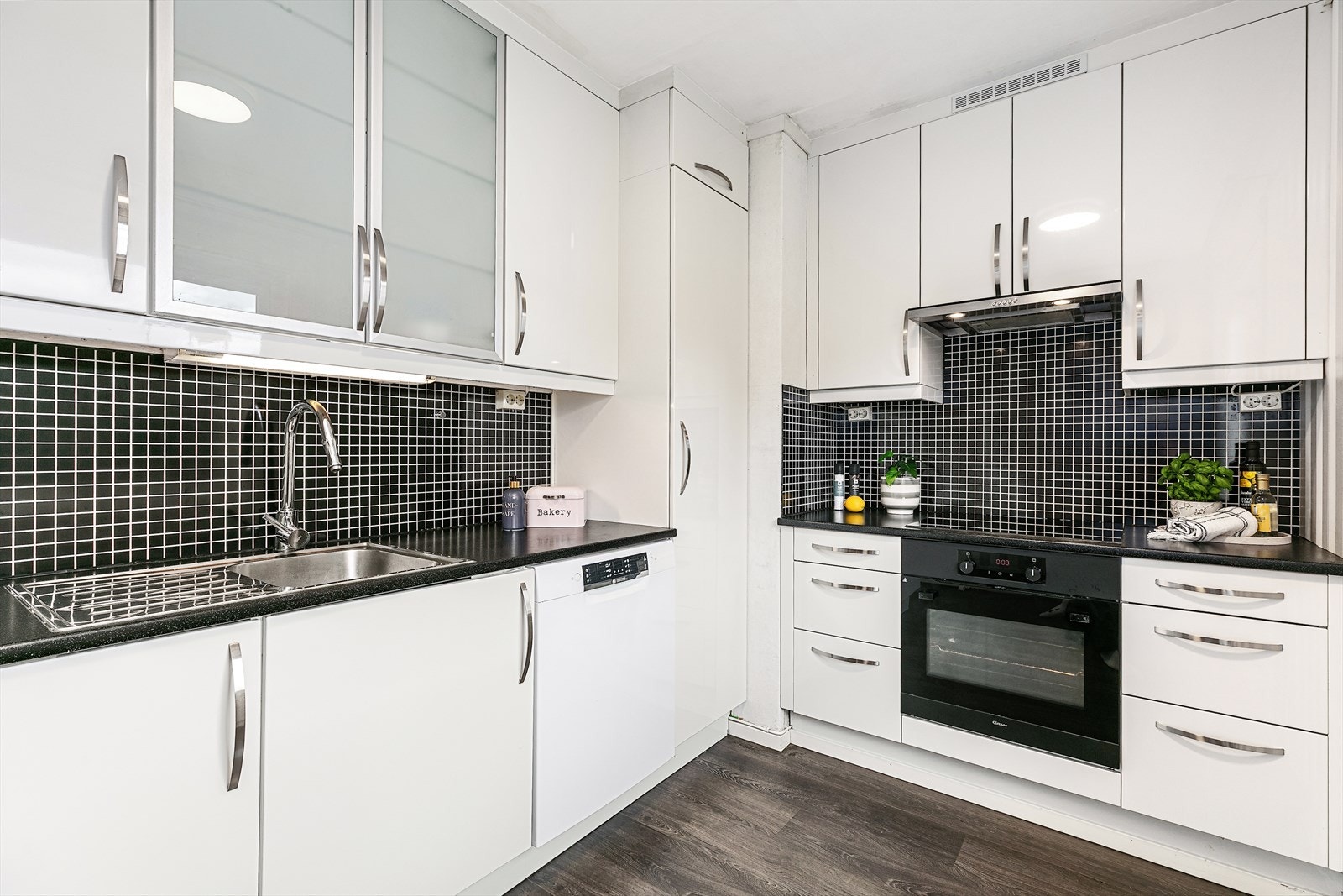 Kjøkkeninnredningen har glatte skapfronter i over- og underskap, belysning, laminat benkeplate, og integrerte hvitevarer som induksjonstopp og stekeovn fra 2022. Galleribilde