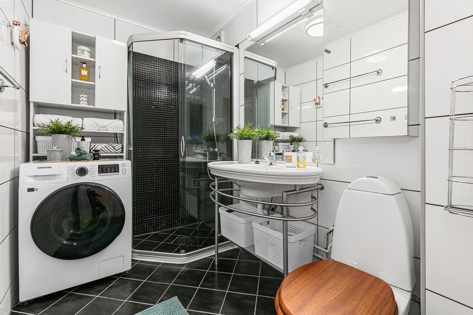 Pent flislagt baderom med varmekabler i gulv. Baderomsinnredningen består av gulvmontert toalett, servant med underhylle, speil, veggskap, dusjnisje i hjørne med skyvedører, samt opplegg for vaskemaskin. Galleribilde