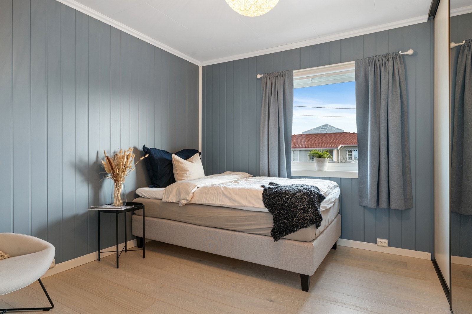 Leiligheten har to soverom. Dette rommet har atkomst fra stuen. Her er det trepanel i en dus blåfarge på veggene. Det er plass til dobbeltseng og småmøbler Galleribilde