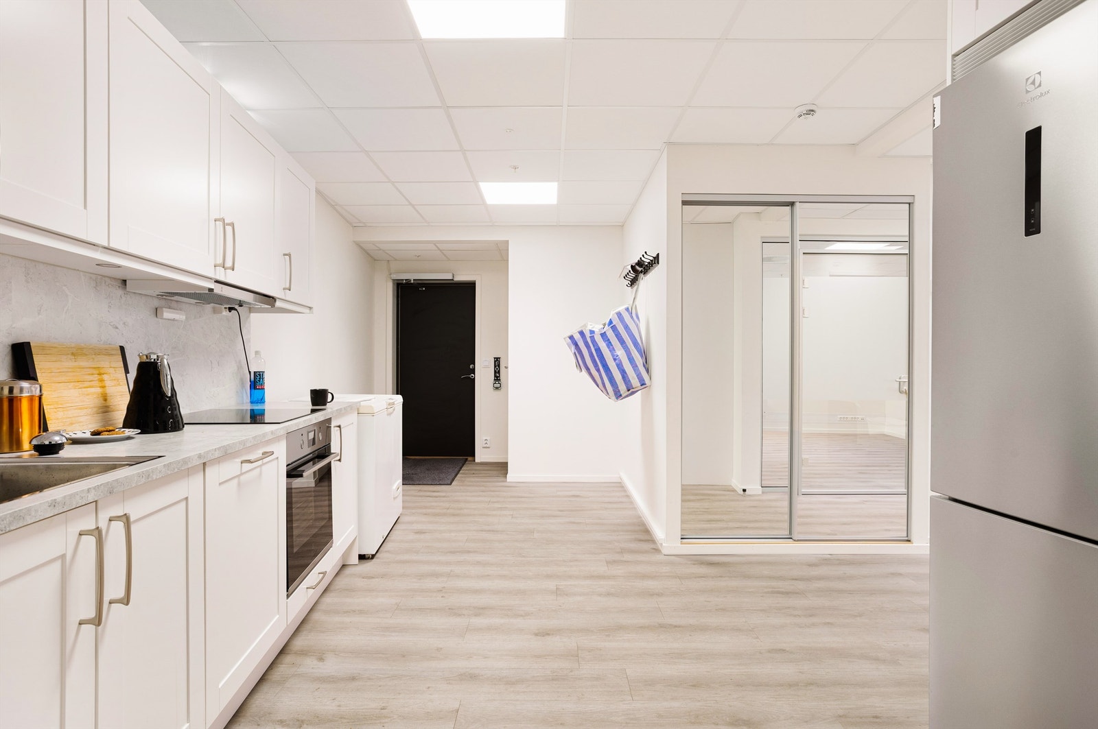 Åpent mingleareal med tekjøkken og skyvedørsgarderobe. Adkomst til heis og garasje. Galleribilde