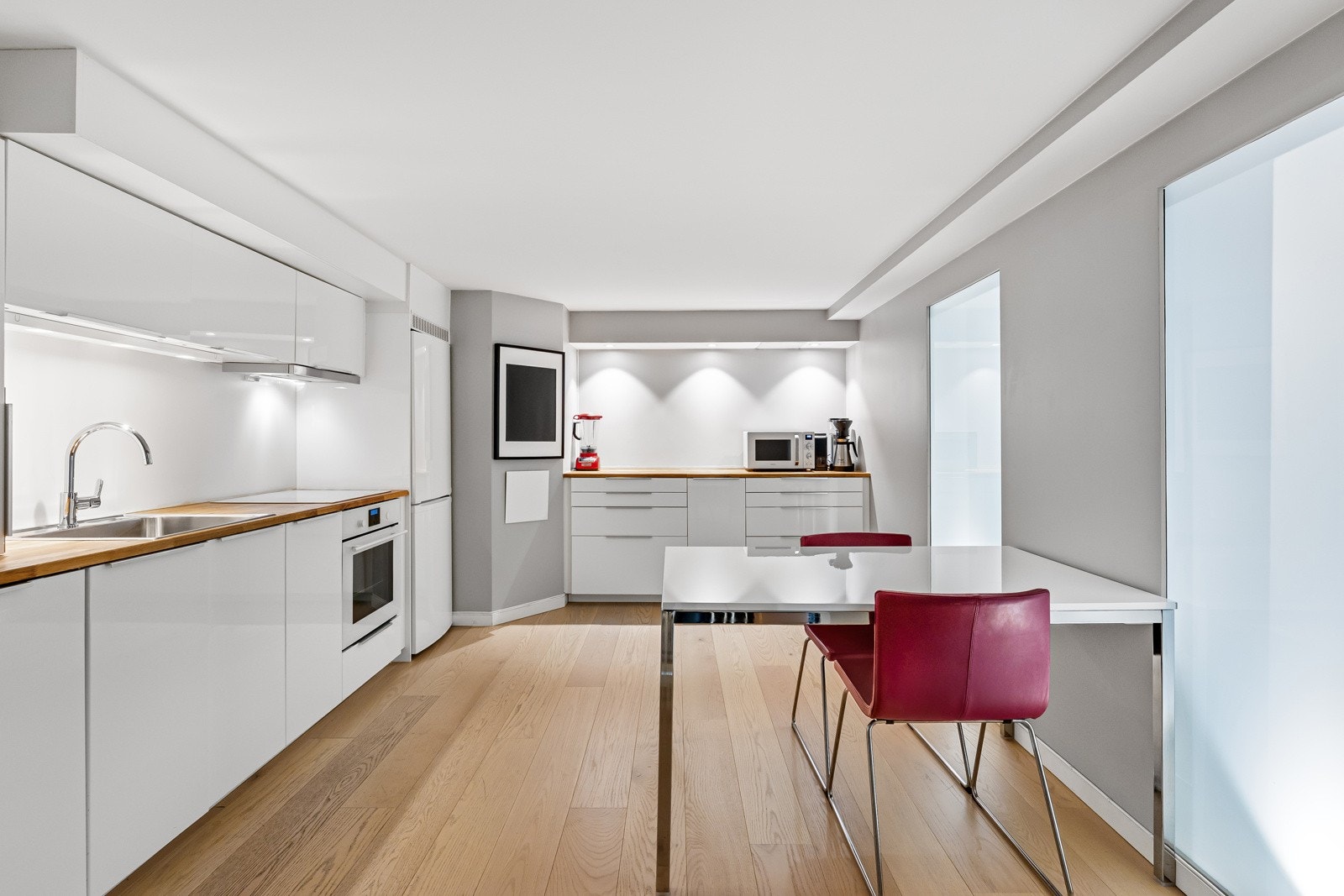 Rommet har et gjennomført, moderne uttrykk med enstavs eikeparkett på gulvet, slette, gråmalte vegger, spiseplass og en stilren kjøkkeninnredning. Galleribilde