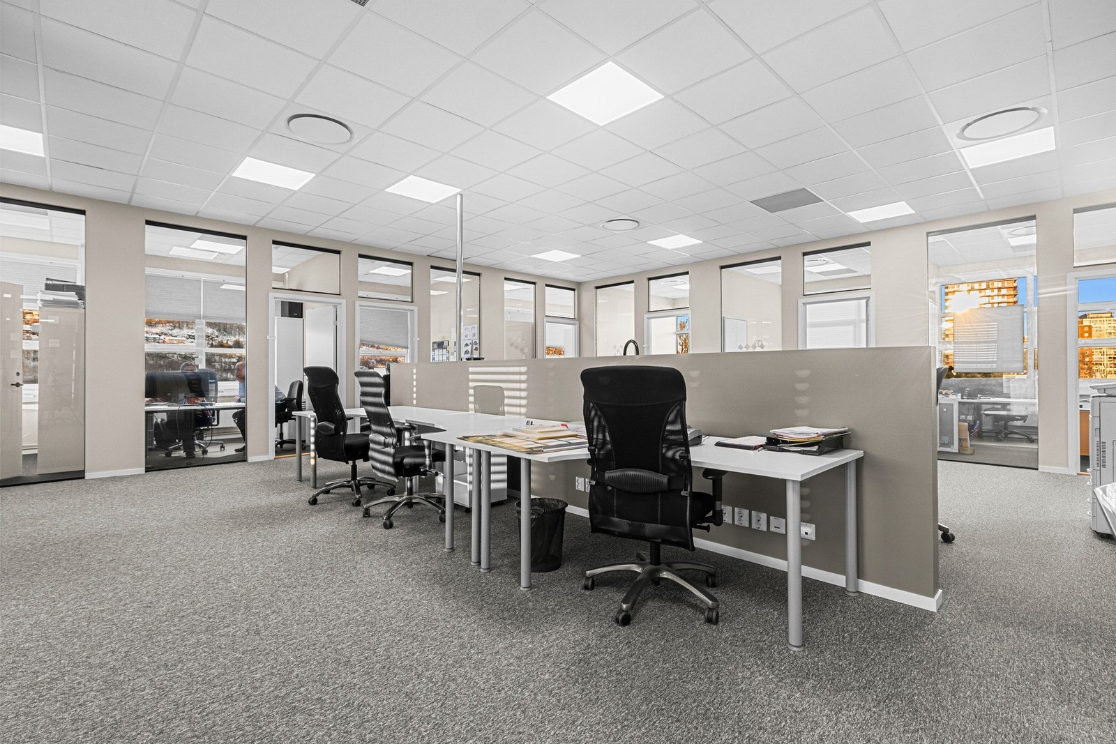 Effektiv planløsning med arbeidsplasser i åpent landskap og cellekontorer langs vindusrekken. Galleribilde