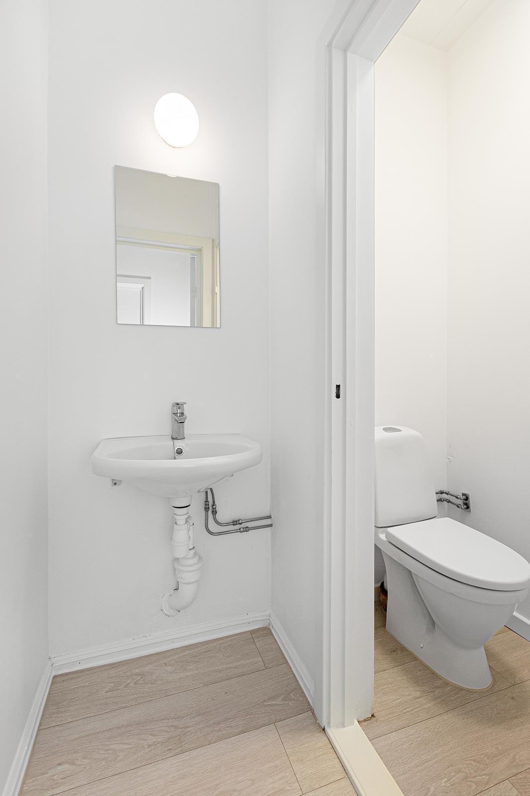 Fint personaltoalett med laminatgulv og lyse overflater Galleribilde